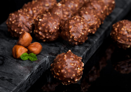 黑色大理石底有桃子片和薄荷叶的豪华巧克力糖果背景图片