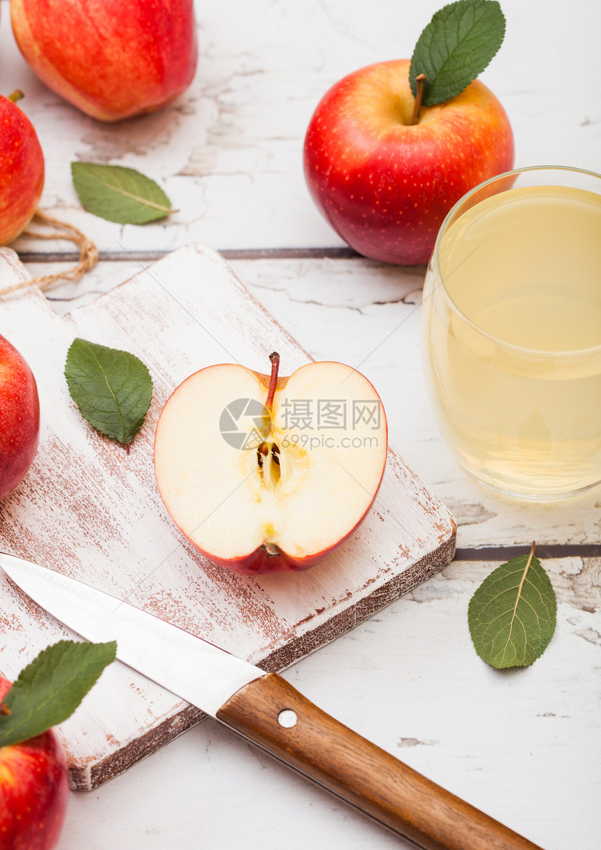 玻璃杯新鲜有机苹果汁红在砍刀板上木制背景图片