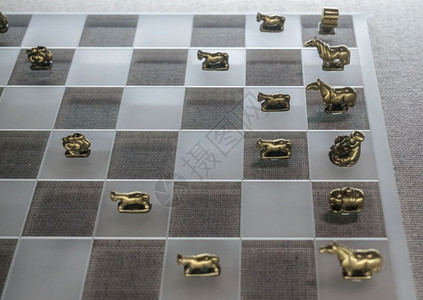 现代玻璃棋盘上的古老金属象棋元件背景图片