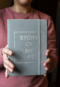 女人拿着笔记本写我人生故事的笔记个人回忆录概念手拿着书背景图片