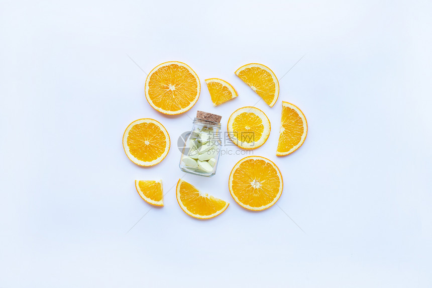 白底带橙果片的维生素c瓶和药丸图片