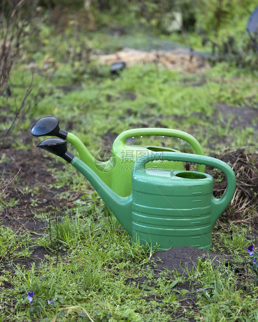 花园湿土上的2个绿水罐图片