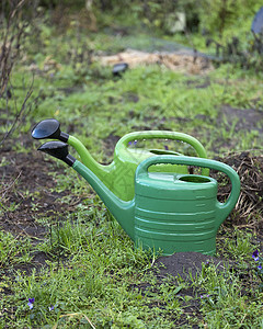 花园湿土上的2个绿水罐高清图片