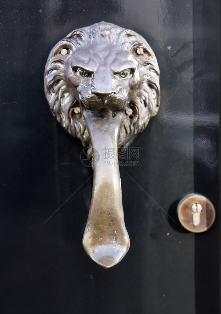 以狮子头为形式的铜门敲器在旧黑上长舌头的狮子图片