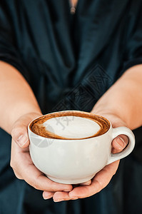 女手举着一杯咖啡热卡布奇诺上面有漂亮的牛奶近镜头高清图片