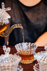 手把茶从壶倒到美丽的杯高清图片