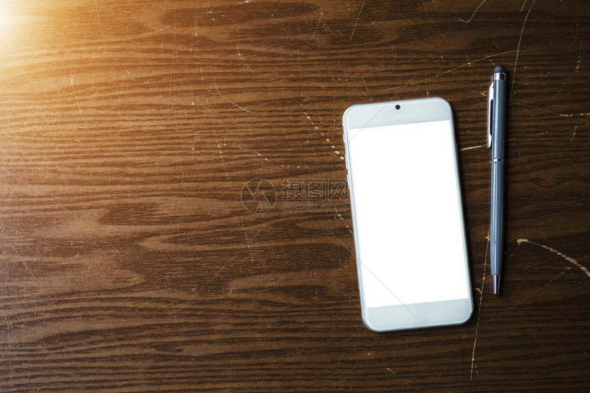手机用笔挂在木制桌子上技术和商业背景图片