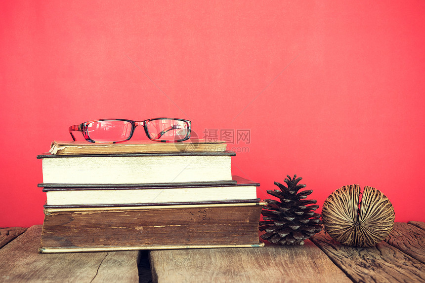 红色或粉背景的玻璃和松子种的旧书堆古老生命图片