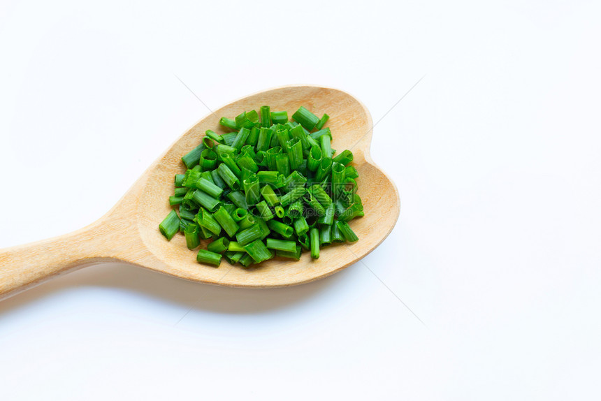 白背景上的绿洋葱和心形勺子图片