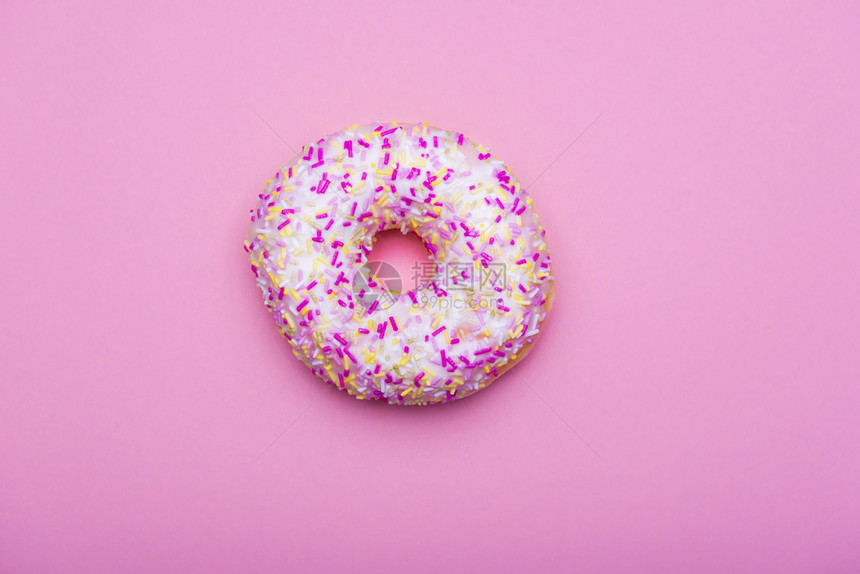 甜圈白色涂料和多彩的喷洒在粉红色的纸面背景上最小的风格超过著名的甜点图片