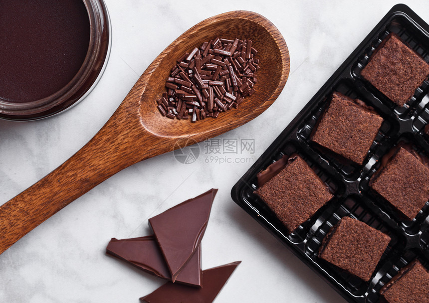 大理石板上巧克力饼干短甜点加罐液巧克力和木勺图片