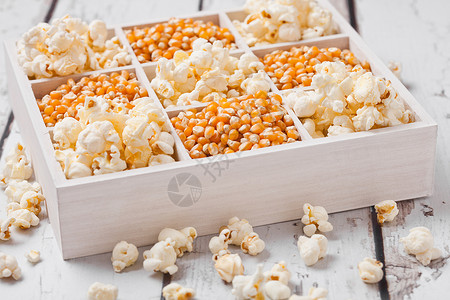浅底白木盒中的鲜金甜玉米种子和爆花背景图片