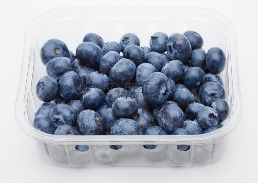 白色背景塑料容器中的新鲜健康有机蓝莓图片