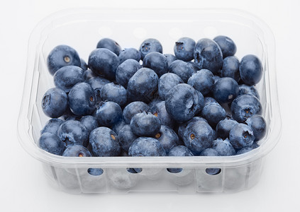 白色背景塑料容器中的新鲜健康有机蓝莓高清图片