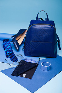 手提包袋蓝色时装风格仍以蓝背景为生活设置并配有鞋领带眼镜袋笔和记本背景