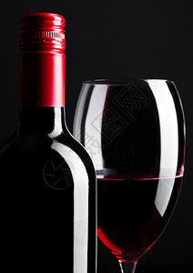 红色酒瓶和玻璃杯黑色背景图片