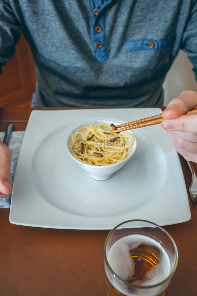 无法辨认的人吃意大利面和用筷子的板球男人吃意大利面和板球图片