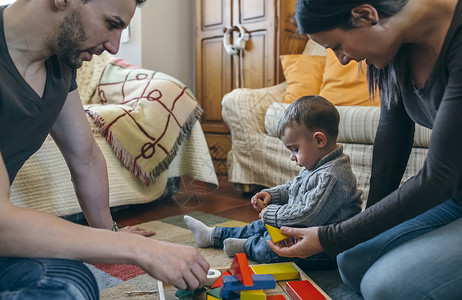 父亲与孩子玩父母在起居室和幼儿玩木制游戏父母在与幼儿玩木制游戏父母在与幼儿玩木制游戏背景