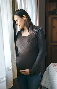 孕妇抚摸肚子看着窗外图片