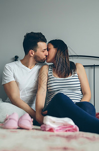 年轻男子在卧室中亲吻其怀孕妻子男人亲吻其怀孕妻子高清图片