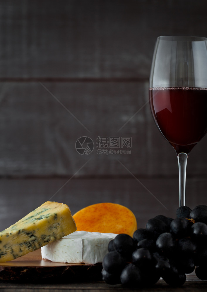 玻璃红葡萄酒配有奶酪选择和木制葡萄图片