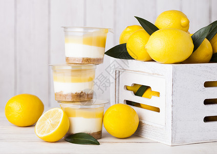 塑料杯加柠檬奶油和饼干甜点白木盒子中生柠檬背景图片