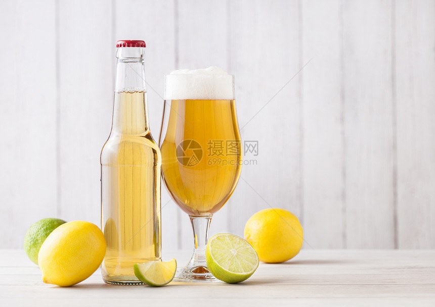 和啤酒瓶杯在轻木背景上加柠檬和石灰图片