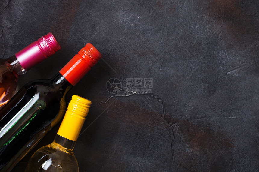 石头厨房桌背景上的红白和粉玫瑰酒瓶图片