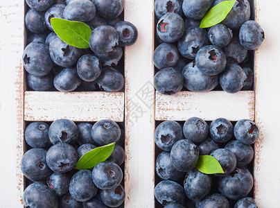 鲜生有机蓝莓在厨房背景上用旧木箱中的叶子背景图片