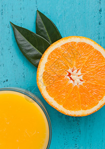 蓝色木质背景的生橙色玻璃新鲜的橙色冰凉汁图片