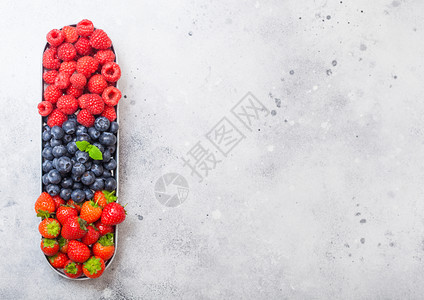 在不锈钢盘中的新鲜有机果子在石质厨房桌背景上文本空间顶视图草莓蓝和薄片叶图片