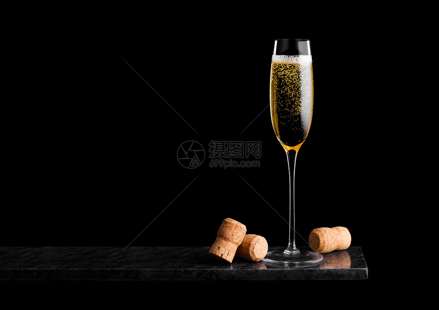 优雅的黄色香槟杯子黑大理石板上的软木塞在黑色大理石板上图片