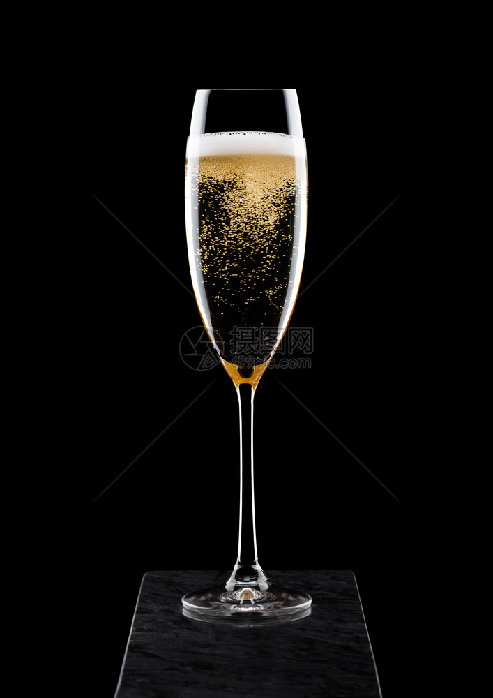 优雅的黄色香槟杯子黑大理石板上有泡图片