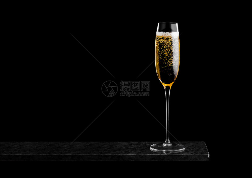 优雅的黄色香槟杯子黑大理石板上的泡黑色背景图片