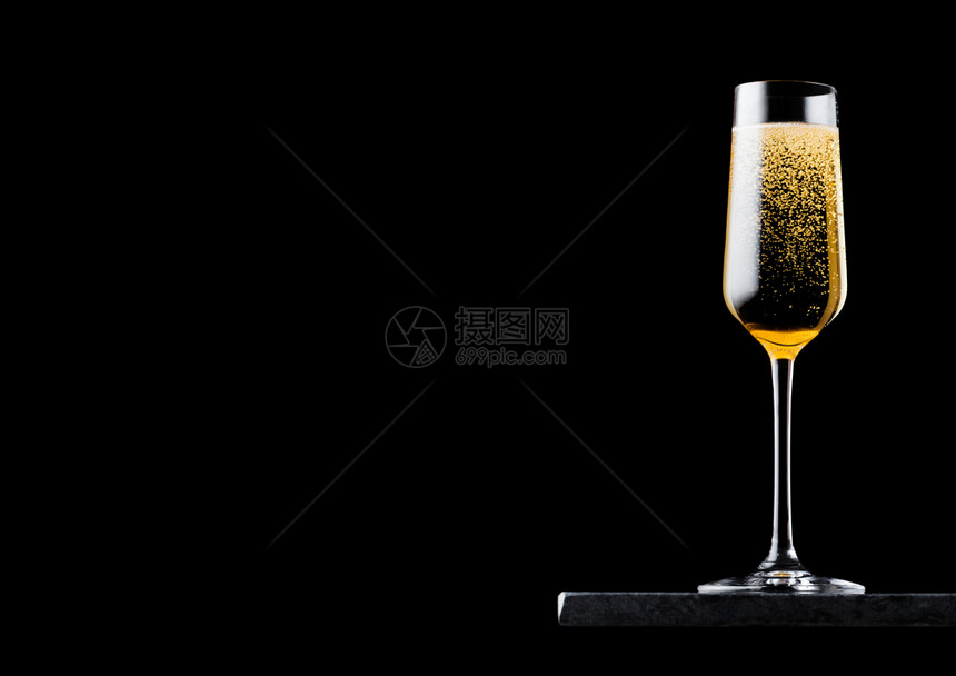 优雅的黄色香槟杯子黑大理石板上的泡黑色背景图片