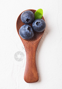 鲜生有机蓝莓小木勺叶子白色厨房背景食物概念图片