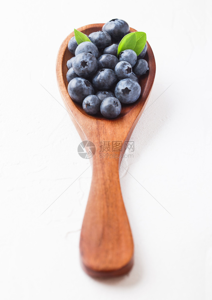 鲜生有机蓝莓木勺叶子白色厨房背景食物概念图片
