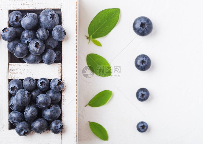 鲜生有机蓝莓在厨房背景上用旧木箱中的叶子图片