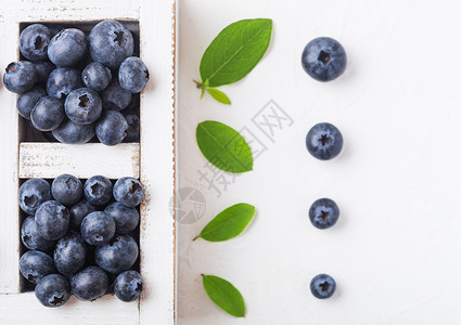 鲜生有机蓝莓在厨房背景上用旧木箱中的叶子背景图片