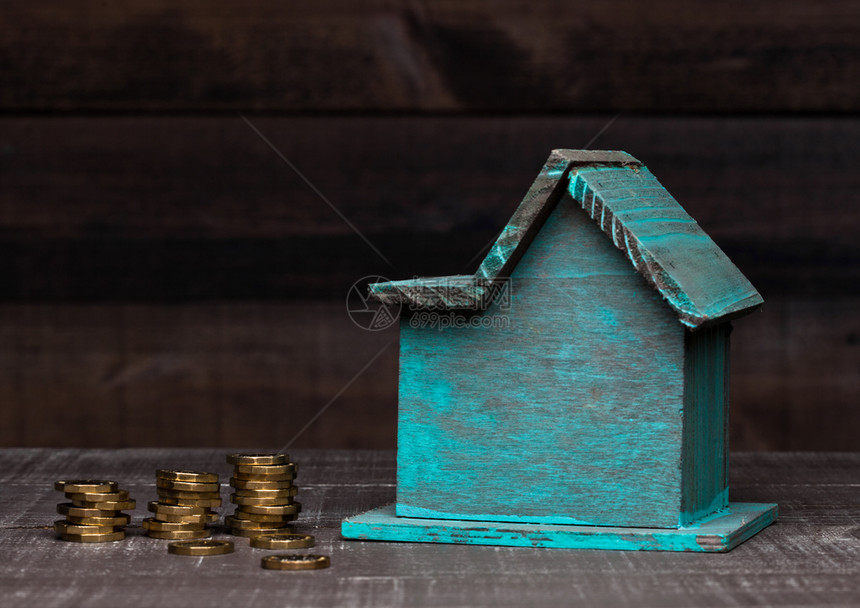 木制的房子模型和硬币旁边的概念文本图片