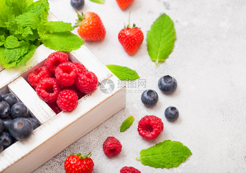 在厨房桌背景的白木盒子中隔离的新鲜有机果子关闭草莓蓝和薄荷叶图片