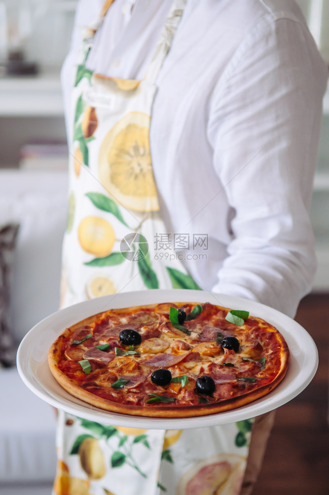 黑橄榄和意大利酱披萨放在服务员手中的盘子上图片