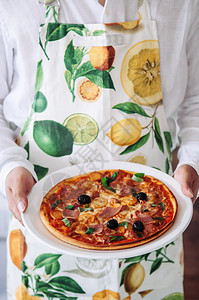 黑橄榄和意大利酱披萨放在服务员手中的盘子上图片