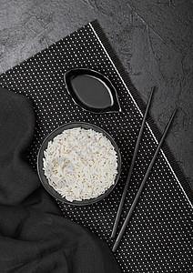 黑碗加煮有机巴斯马蒂茉米饭黑筷子和甜豆酱在竹子垫上的白图片