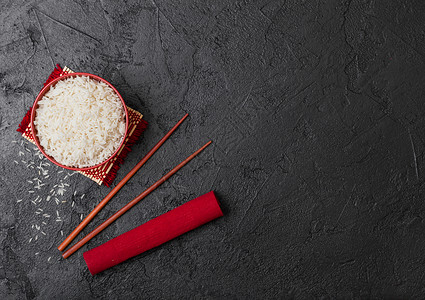 红碗加煮的有机巴斯马提茉米饭红筷子和甜豆酱加竹制地垫红皮巾加黑石图片