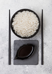 黑碗有煮的机巴斯马蒂茉米饭有黑筷子和甜豆酱放在石垫上浅的厨房桌底图片