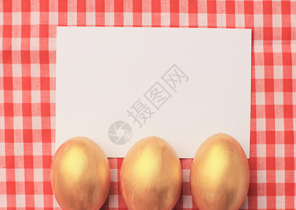 红桌布背景的金色鸡蛋图片