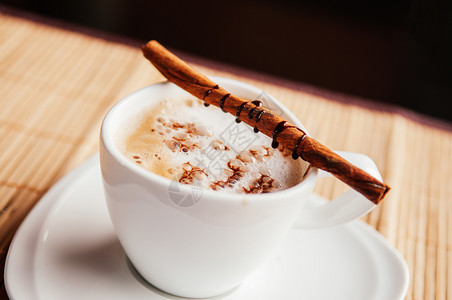 白杯咖啡加肉桂棒和木桌上巧克力酱图片