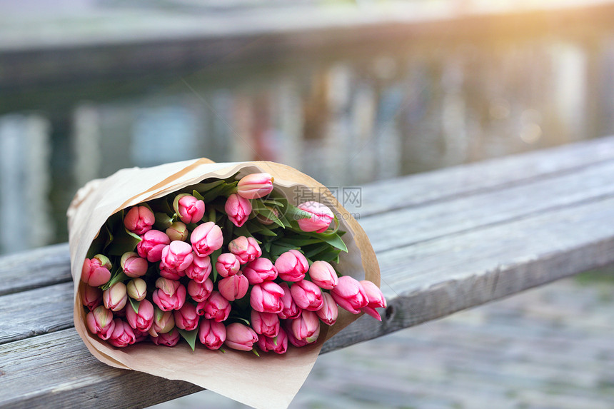 美丽的粉红色郁金香花束躺在长椅上图片
