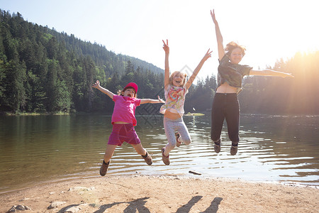 快乐的孩子们在湖边跳高背景图片